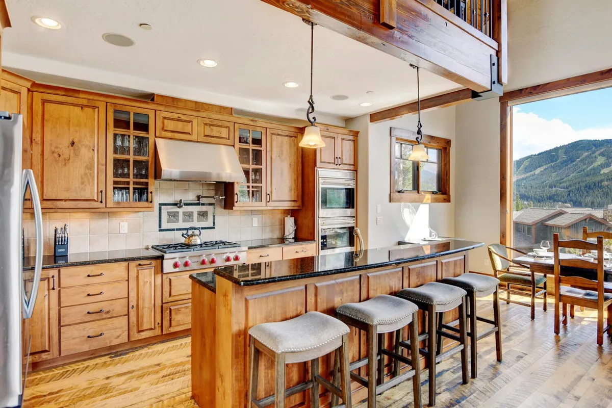 A beautifully appointed kitchen with a standout island, large windows letting in natural light, and high-end stainless steel appliances. Wooden cabinetry and inviting design details create a warm, functional space ideal for cooking together.