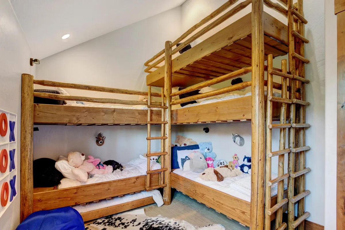 A playful custom bunk room with multiple bunk beds, soft stuffed animals, and ladders, designed for fun and comfort. The space is filled with youthful energy, inviting children to share stories and laughter.